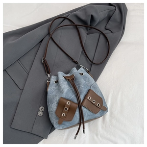 Close-up of vintage denim bucket bag with leather patchwork and drawstring closure