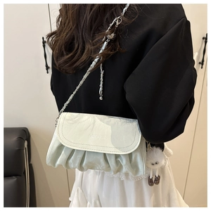Detail of mint green soft leather crossbody bag with chain strap and plush pendant