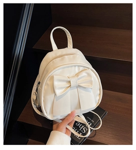 Detailed view of the large white bow and premium PU leather texture on the mini backpack