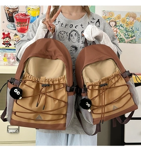 Size comparison of two color-block canvas backpacks with plush charms and bungee cords
