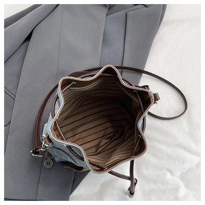 Close-up of denim bucket bag interior showing striped lining and brown leather drawstring