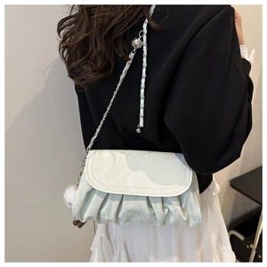 Detail of mint green pleated crossbody bag with chain strap and decorative fluffy balls