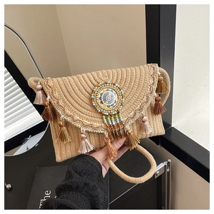 Close-up of bohemian straw crossbody bag with colorful tassels and ethnic bead details