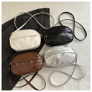 Flat lay of minimalist crossbody bags in ivory, black, brown, and silver glossy finishes