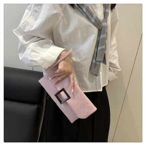 Detail of pink suede envelope clutch bag featuring a large black square buckle and wristlet