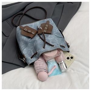 Spacious interior of blue denim bucket bag showing phone, umbrella, and cosmetics