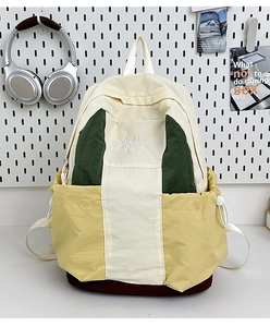 Detailed view of color block nylon backpack featuring embroidery and side drawstring pockets