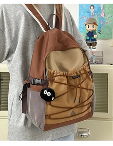 Detail of color-block canvas backpack with elastic bungee cords and mesh side pocket