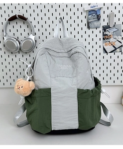 Detail view of contrast color nylon backpack with plush bear charm and brand logo