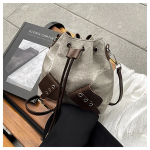 Detailed view of retro denim bucket bag with brown leather drawstring on a wooden bench