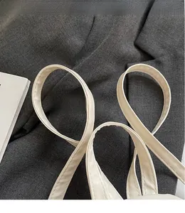 Detail of smooth synthetic leather shoulder straps and stitching on a beige mini backpack