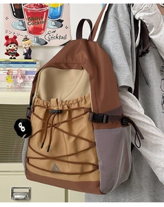 Detail of color-block canvas backpack featuring elastic cord decor and plush pendant charm