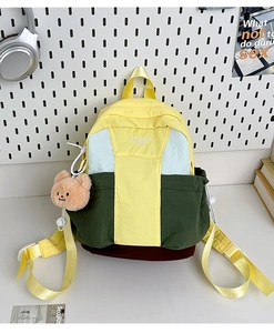 Detail of color-block nylon backpack featuring a bear pendant and embroidered brand logo