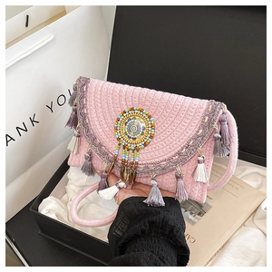 Dettaglio ravvicinato della borsa a tracolla intrecciata rosa con perline e lunghe nappe