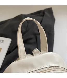 Detail of the reinforced leather handle and stitching on the minimalist beige backpack