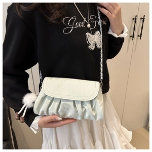 Detail of off-white pleated chain bag with fashion lettering and plush charm accessory