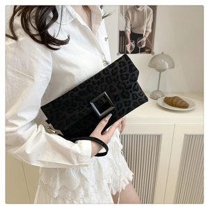Detail of black leopard print clutch bag with large square buckle and wrist strap