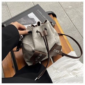 Detail of vintage canvas drawstring bucket bag with leather trim on a wooden bench