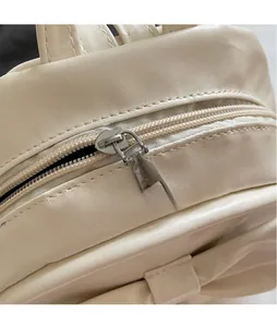 Close-up of polished silver metal zipper and smooth cream leather texture on backpack