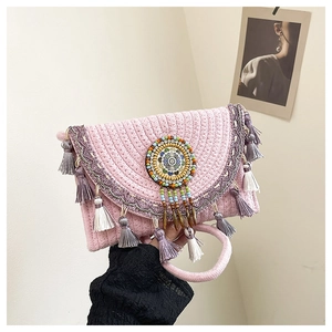 Dettaglio della borsa in paglia rosa con nappe etniche e decorazioni di perline