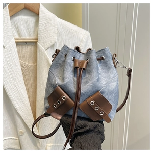 Detail of blue denim bucket bag with brown leather drawstring and metal eyelets