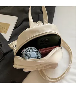 Interior storage view of cream mini bow backpack showing phone and wallet capacity