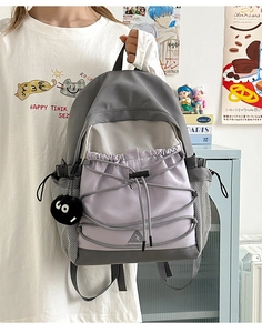 Detail of color-block canvas backpack with elastic cords and plush coal ball keychain