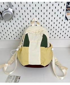 Detail of color-block nylon backpack featuring embroidered brand logo and side pockets