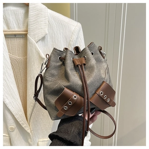 Close-up of retro gray canvas bucket bag with brown leather details and drawstring closure