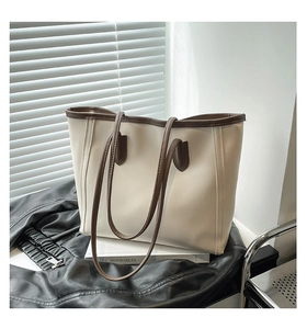 Detail of cream tote bag with brown handles and a book in soft window lighting