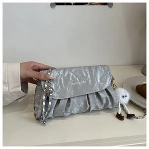 Détail du sac bandoulière argenté plissé avec chaîne en métal et breloque peluche