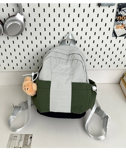 Detail of color-block nylon backpack with plush bear pendant and student school style