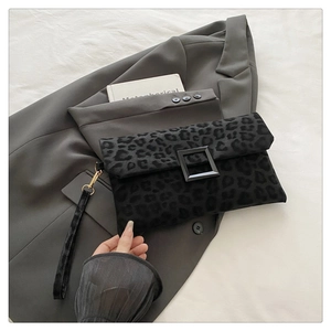 Close-up of black leopard print envelope clutch with matte buckle and wrist strap