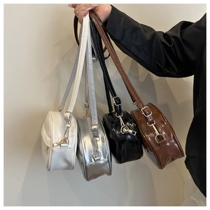 Collection of round crossbody bags in white, silver, black, and brown with gold zippers