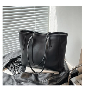 Detail of minimalist black faux leather tote bag with fine texture and slim straps