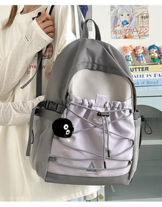 Detail of grey and lavender canvas backpack featuring adjustable buckle and drawstring