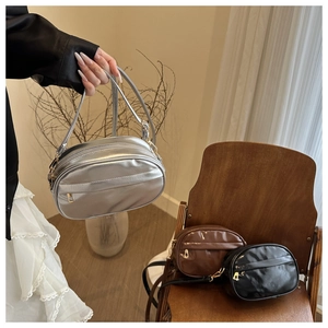 Minimalist soft leather crossbody bags in silver, black and coffee on a wooden chair