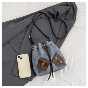 Detail view of light blue denim bucket bag with brown leather drawstrings and size reference