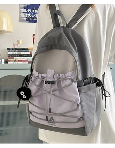 Close-up of color block canvas backpack with grey and lavender panels and mesh side pocket