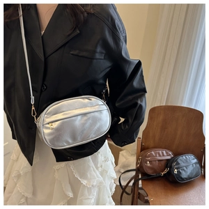 Close-up of stylish oval crossbody bags in silver, brown, and black with metal zippers