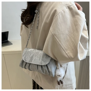 Detail of silver pleated crossbody bag with chain strap and cute monster charm