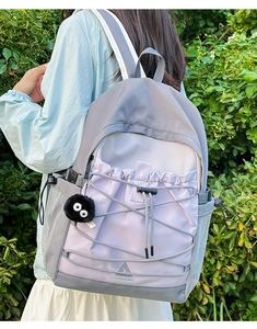 Outdoor shot showing details of the purple canvas backpack with logo and mesh side pocket