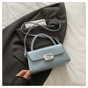 Detail of light blue crossbody bag featuring a silver G-shaped metallic lock buckle