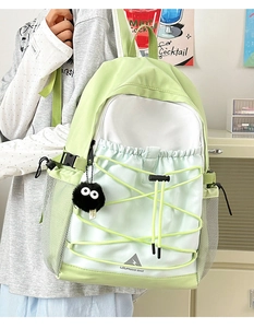 Detail of mint green and white canvas backpack featuring cross-drawstring and plush charm