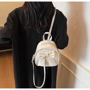 Detail of cream white mini backpack with large bow decoration and adjustable straps