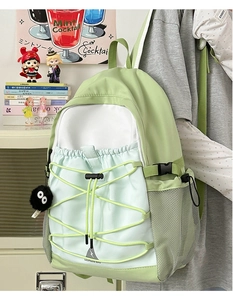 Close-up of mint green and white canvas backpack with drawstring pocket and plush charm