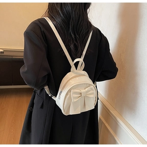 Detailed view of a cream bow backpack on a model showing mini size and style