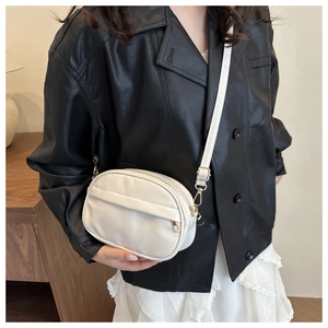 Detailed view of model wearing white PU leather crossbody bag with golden double zippers