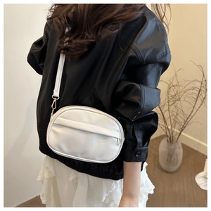 Close-up of white minimalist crossbody bag with adjustable strap and metal hardware detail