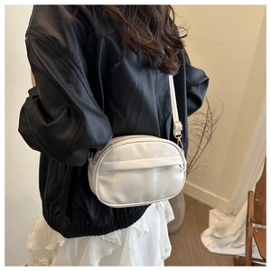 Back view of a minimalist white crossbody bag with gold buckle on a model in a leather jacket